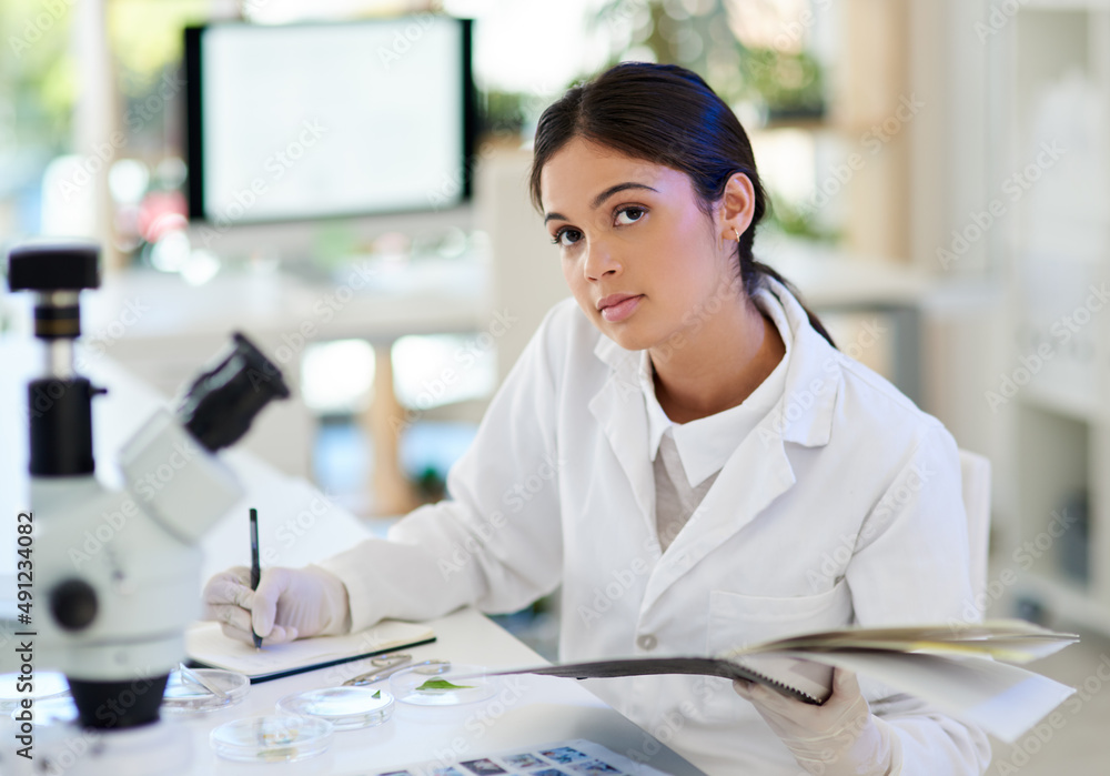 Poster ive made quite a few new discoveries today. portrait of a young scientist writing notes while workin