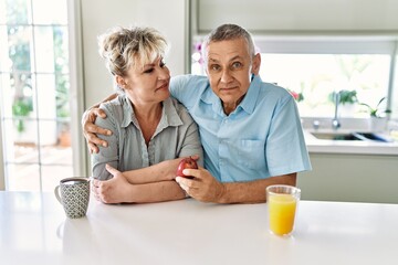 Fototapeta na wymiar Senior caucasian couple smiling happy having breakfast at the kitchen.