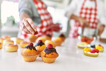 Couple cooking sweets at the kitchen.