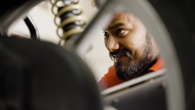 handheld close up head shot shot of bike mechanic reparing motorbike at garage - concept of Hard working, repair service and dedication