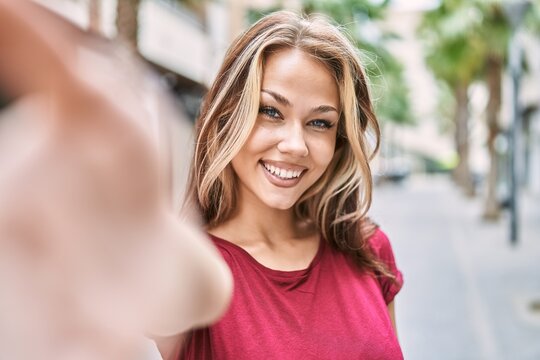 Young caucasian girl smiling happy making selfie by the camera at the city.