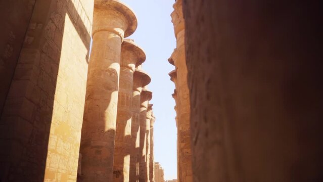 Large stone pillars in the Hypostyle Hall, Luxor Egypt. Intricately detailed with carved hieroglyphs. 
Low angle and a small camera movement.