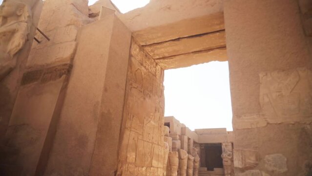 Outside of the tall entry way into the Kamak Temple with carved details and hieroglyphs on the walls. Slow pan up at an angle shows the grand scale of the structure. 