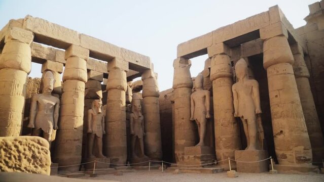 Tall pillars and pylons with rock statues in the Karnak Temple, Luxor, Egypt. 
Slow camera movement backwards.
