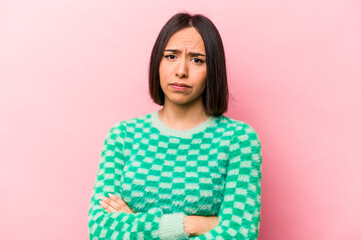 Fototapeta premium Young hispanic woman isolated on pink background suspicious, uncertain, examining you.