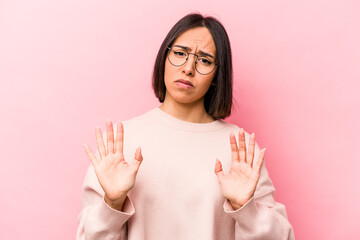Young hispanic woman isolated on pink background rejecting someone showing a gesture of disgust.