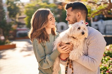 Man and woman holding dog standing together at park