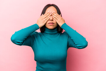 Young hispanic woman isolated on pink background afraid covering eyes with hands.