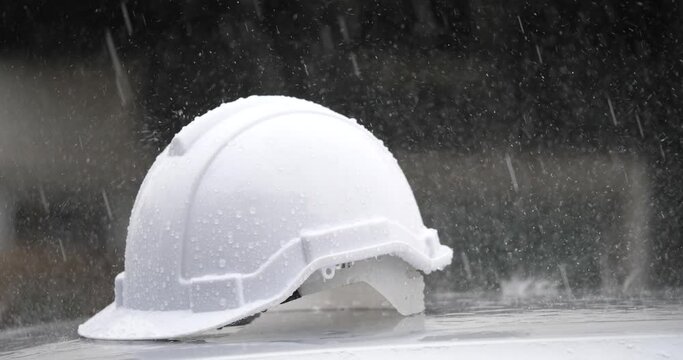 Construction site with rain concept, white helmet with heavy rain, rainstorm and construction	