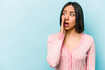 Fototapeta premium Young hispanic woman isolated on blue background is saying a secret hot braking news and looking aside