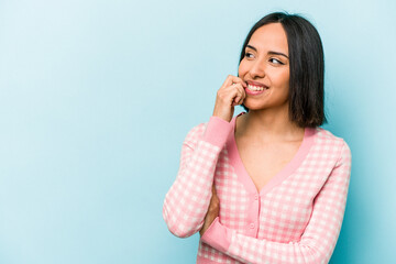 Fototapeta premium Young hispanic woman isolated on blue background relaxed thinking about something looking at a copy space.