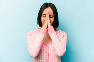 Young hispanic woman isolated on blue background holding hands in pray near mouth, feels confident.