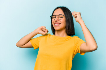 Young hispanic woman isolated on blue background celebrating a special day, jumps and raise arms with energy.