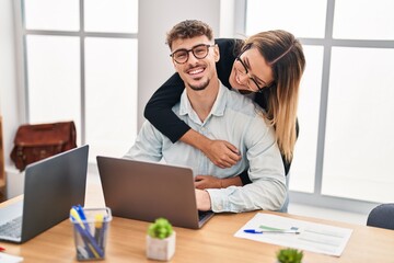 Obraz premium Young man and woman business workers hugging each other working at office