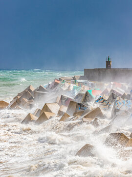 close up view of the breakwater and lighthouse during a seastorm in the afternoon. Llanes, Asturias, Spain