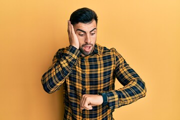 Young hispanic man wearing casual clothes looking at the watch time worried, afraid of getting late