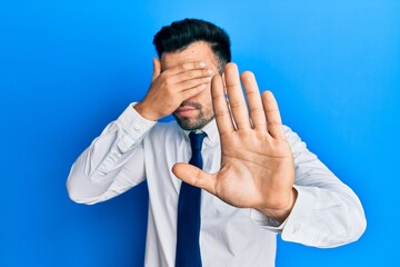 Young hispanic man wearing business clothes covering eyes with hands and doing stop gesture with sad and fear expression. embarrassed and negative concept.