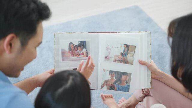 Asian family look at photographs on old picture album recalls the past