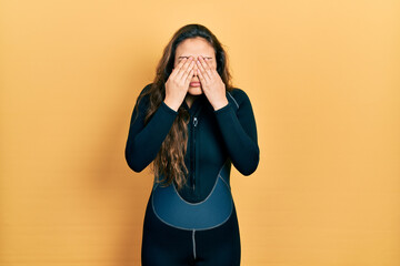 Young hispanic girl wearing diver neoprene uniform rubbing eyes for fatigue and headache, sleepy...