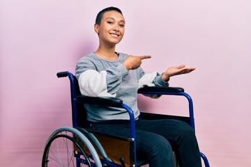 Beautiful hispanic woman with short hair sitting on wheelchair amazed and smiling to the camera...