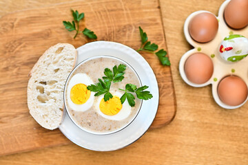Traditional Polish soup served with bread and eggs. Easter decoration. Sour soup - obrazy, fototapety, plakaty