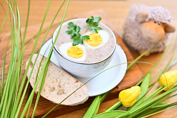 Naklejka premium Traditional Polish soup served with bread and eggs. Easter decoration. Sour soup
