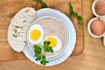 Obraz premium Traditional Polish soup served with bread and eggs. Easter decoration. Sour soup