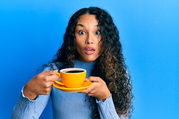 Young latin woman holding coffee clueless and confused expression. doubt concept.