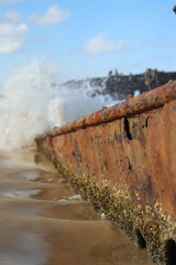 sea waves pound the wreckage of a rusted wrecked ship