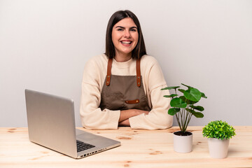 Young caucasian gardener woman working on the table isolated on pink background laughing and having fun.