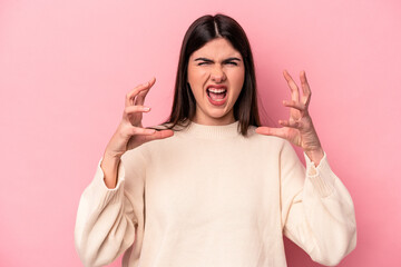 Young caucasian woman isolated on pink background screaming with rage.