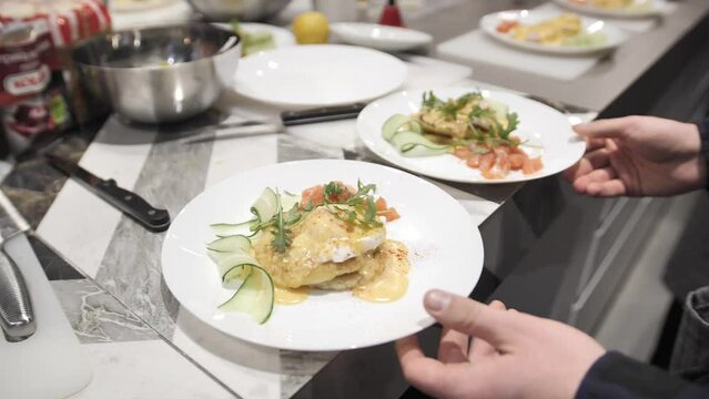 Top View The Waiter Serves Plates Of Food With Poached Egg, Salmon And Cucumber.