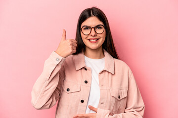 Young caucasian woman isolated on pink background touches tummy, smiles gently, eating and satisfaction concept.