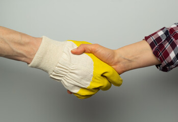 The handshake of a worker in a construction glove and the hand of the customer.