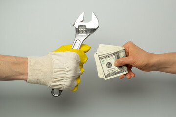 The concept of a plumber's hand with an adjustable wrench and a client with money. Payment for repair work.