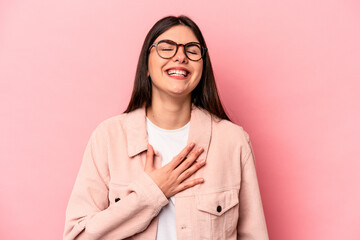 Young caucasian woman isolated on pink background laughs out loudly keeping hand on chest.