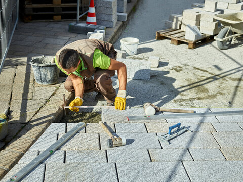 Blue-collar worker measuring paving stones at site