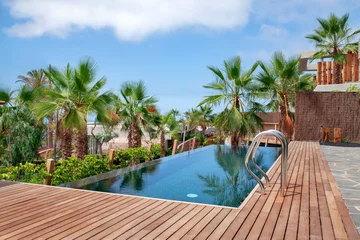 Papier Peint photo les îles Canaries Luxurious swimming pool with clear blue water and surrounded by tropical palm trees and redwood decking, part of a residential property, Abama resort, Tenerife, Canary Islands, Spain