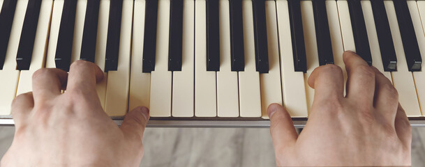 Playing the piano with black and white keys with 2 hands, a first-person perspective from above.