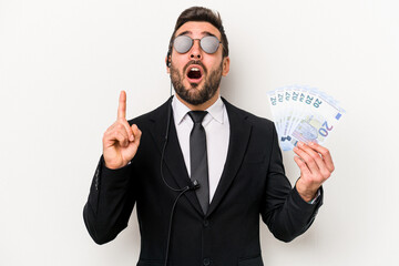 Young caucasian bodyguard man holding banknotes isolated on white background pointing upside with opened mouth.