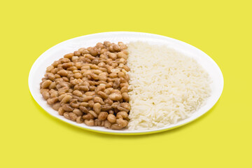 rice dish with beans on isolated yellow background, copy space, traditional brazilian meal
