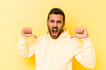 Young caucasian man isolated on yellow background feels proud and self confident, example to follow.