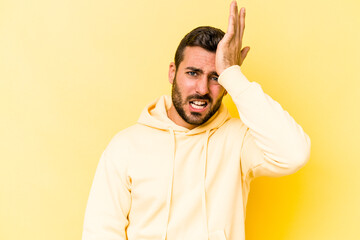 Young caucasian man isolated on yellow background forgetting something, slapping forehead with palm and closing eyes.