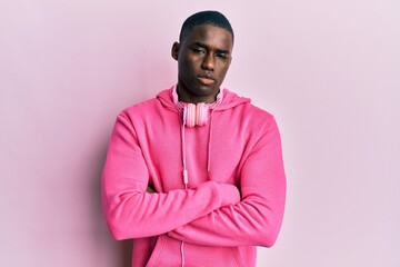 Obraz premium Young african american man wearing gym clothes and using headphones skeptic and nervous, disapproving expression on face with crossed arms. negative person.