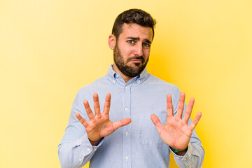 Young caucasian man isolated on yellow background rejecting someone showing a gesture of disgust.