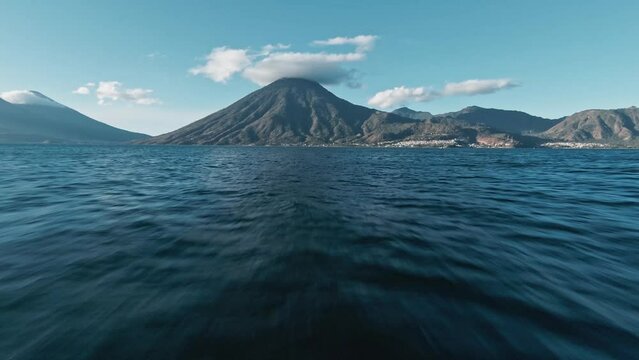 Fast flying towards massive volcano mountain with cloud cap over Lake Atilan, FPV drone view