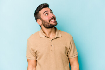 Young caucasian man isolated on blue background relaxed and happy laughing, neck stretched showing teeth.