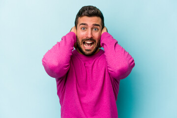 Young caucasian man isolated on blue background screaming with rage.