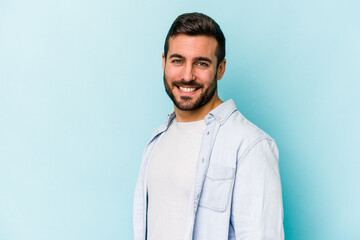 Young caucasian man isolated on blue background confident keeping hands on hips.