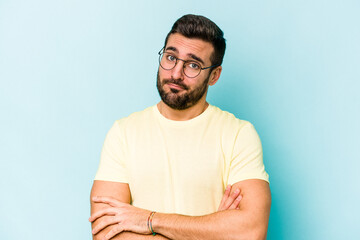 Young caucasian man isolated on blue background unhappy looking in camera with sarcastic expression.